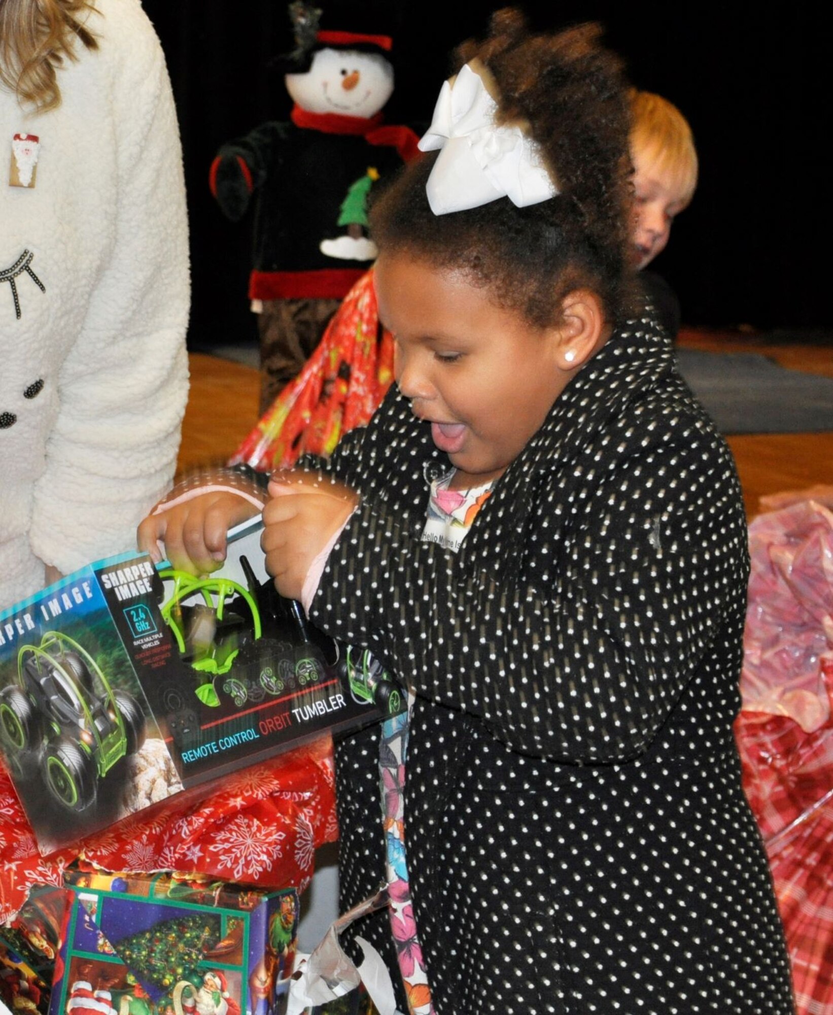 A student from Lucille Moore Elementary School in Panama City, Florida, gasps with surprise as she opens her gift to reveal a new remote control car.  On Dec. 19, members of the Air Force Civil Engineer Center Emergency Management team at Tyndall Air Force Base, Fla., visited with the students at the school to celebrate Christmas early during the “Spread the Joy” event.