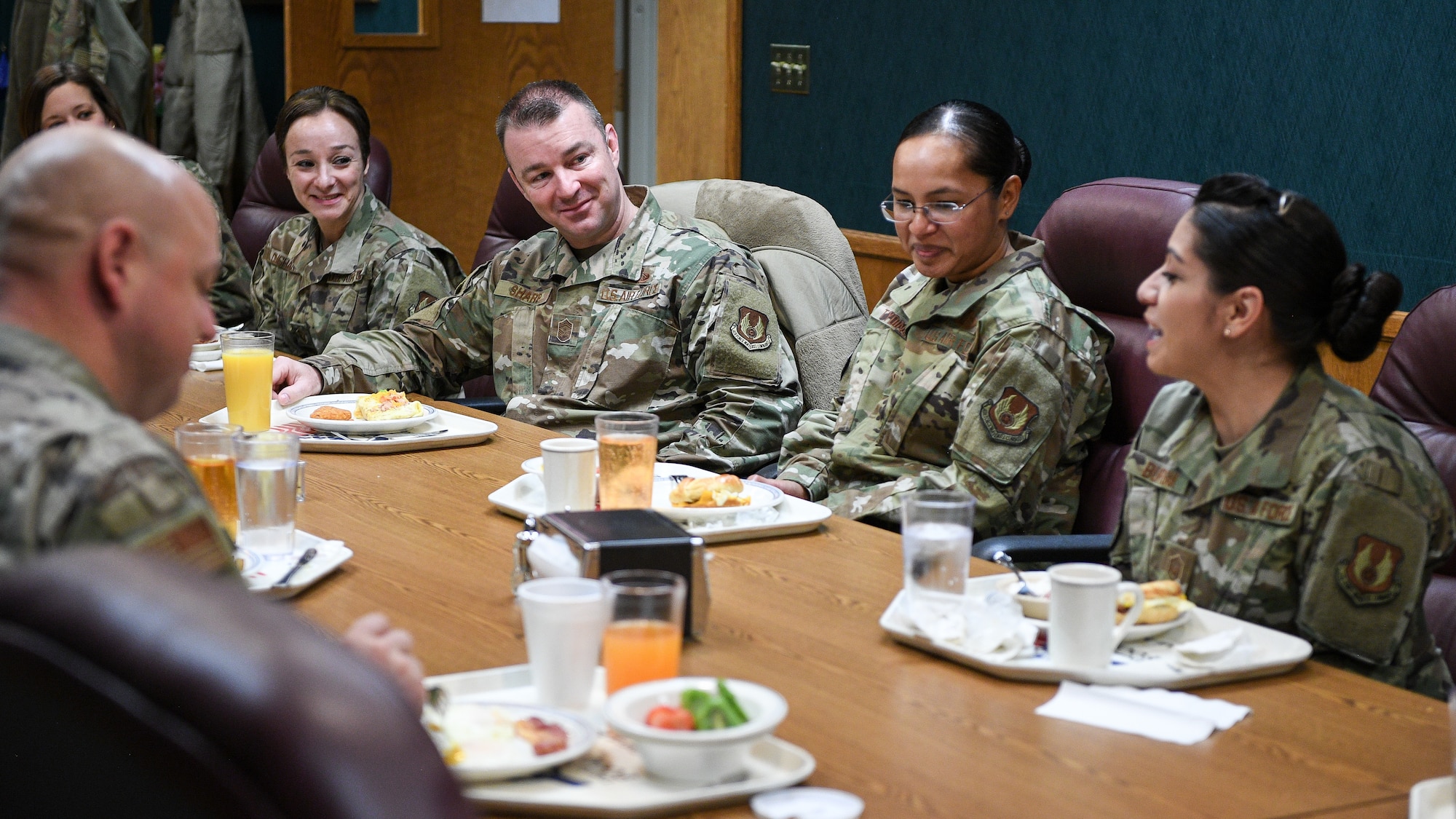 Chief Sharp, AFSC command chief, sits at a table with other Airmen at a table while they eat breakfast.