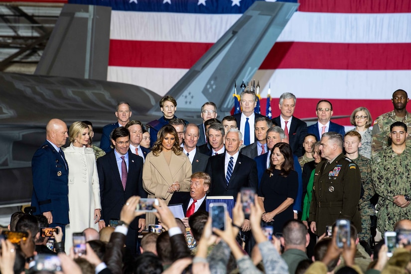 A group of people standing on a stage with a large crowd in the audience.