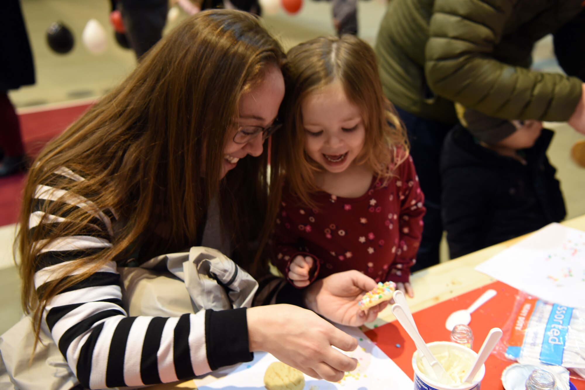 June, daughter of U.S. Air Force Capt. Daniel McKeown, 435th Contingency Response Support Squadron assistant director of operations, expresses delight as she and her mother, Margery, decorate cookies together during the Rudolph the Red Nosed Herc event at Ramstein Air Base, Germany, Dec. 20, 2019.