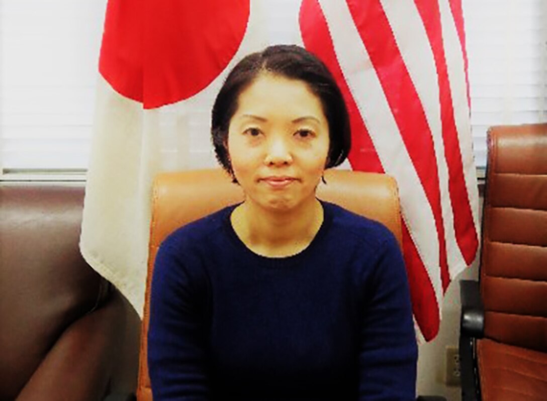 Megumi Ikeda poses in front of the Japanese and U.S. flags.