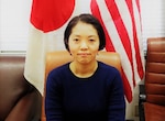 Megumi Ikeda poses in front of the Japanese and U.S. flags.