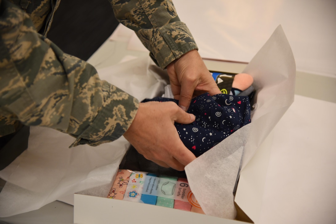 Col. Gary Hayward, 14th Mission Support Group commander, places a shirt into a box to be wrapped Dec. 19, 2019, on Columbus Air Force Base, Miss. Airmen, spouses, and community members of Columbus came together at the Columbus Club to volunteer and show their support for the Happy Irby Holiday Wrap. (U.S. Air Force photo by Airman 1st Class Jake Jacobsen)