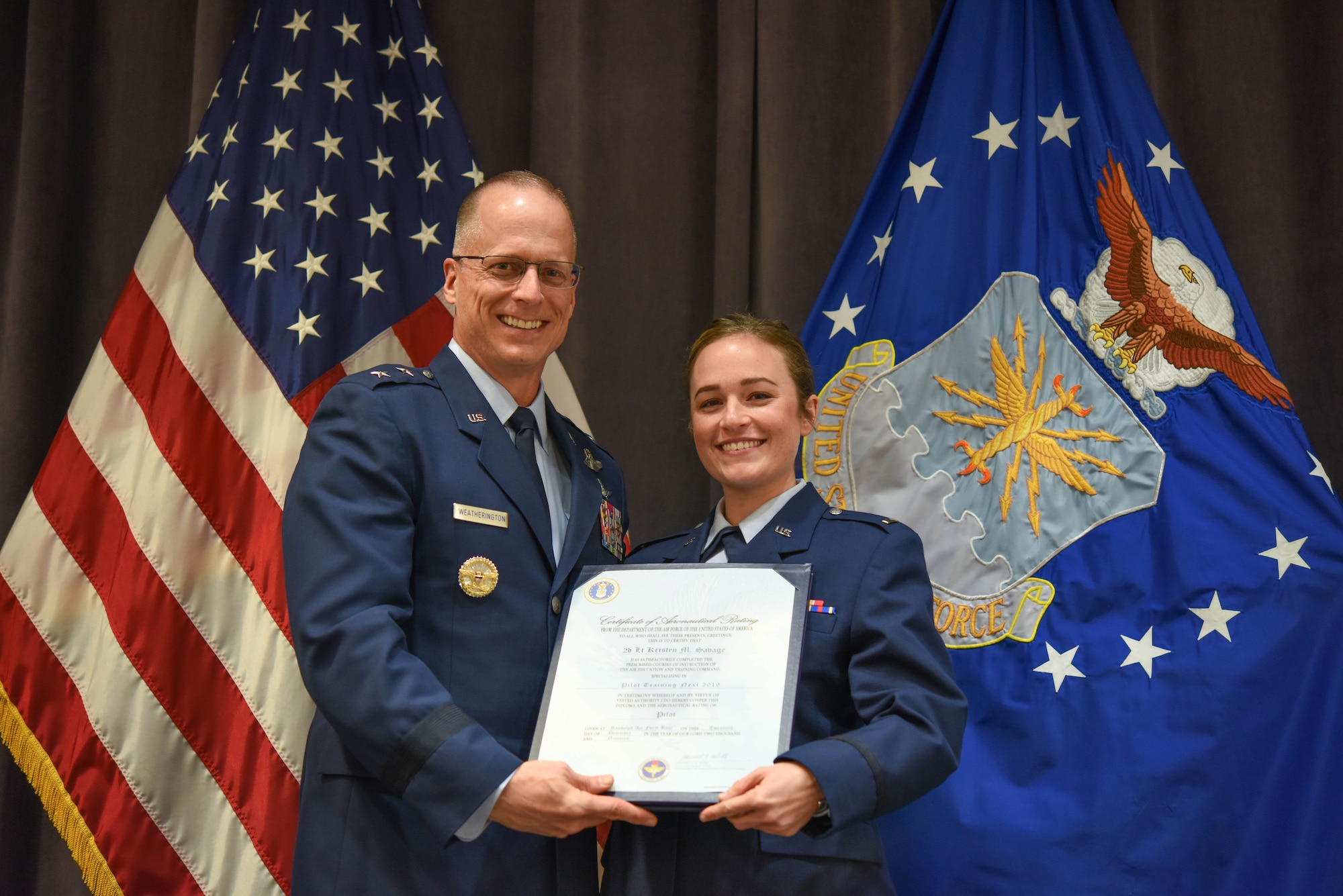 Maj. Gen. Mark Weatherington, Air Education and Training Command deputy commander, presents 2nd Lt. Kristen Savage with her pilot’s wings during a dual commissioning and “winging” ceremony Dec. 19, 2019, at Maxwell Air Force Base, Alabama. Savage was a student pilot who graduated PTN version 2, an Air Education and Training Command program to explore what is possible in training with the use of innovative technology and how it can be applied to not only pilot training but also to training across AETC.  She earned her wings, but couldn’t wear them until she commissioned. (U.S. Air Force photo by Staff Sgt. Quay Drawdy)