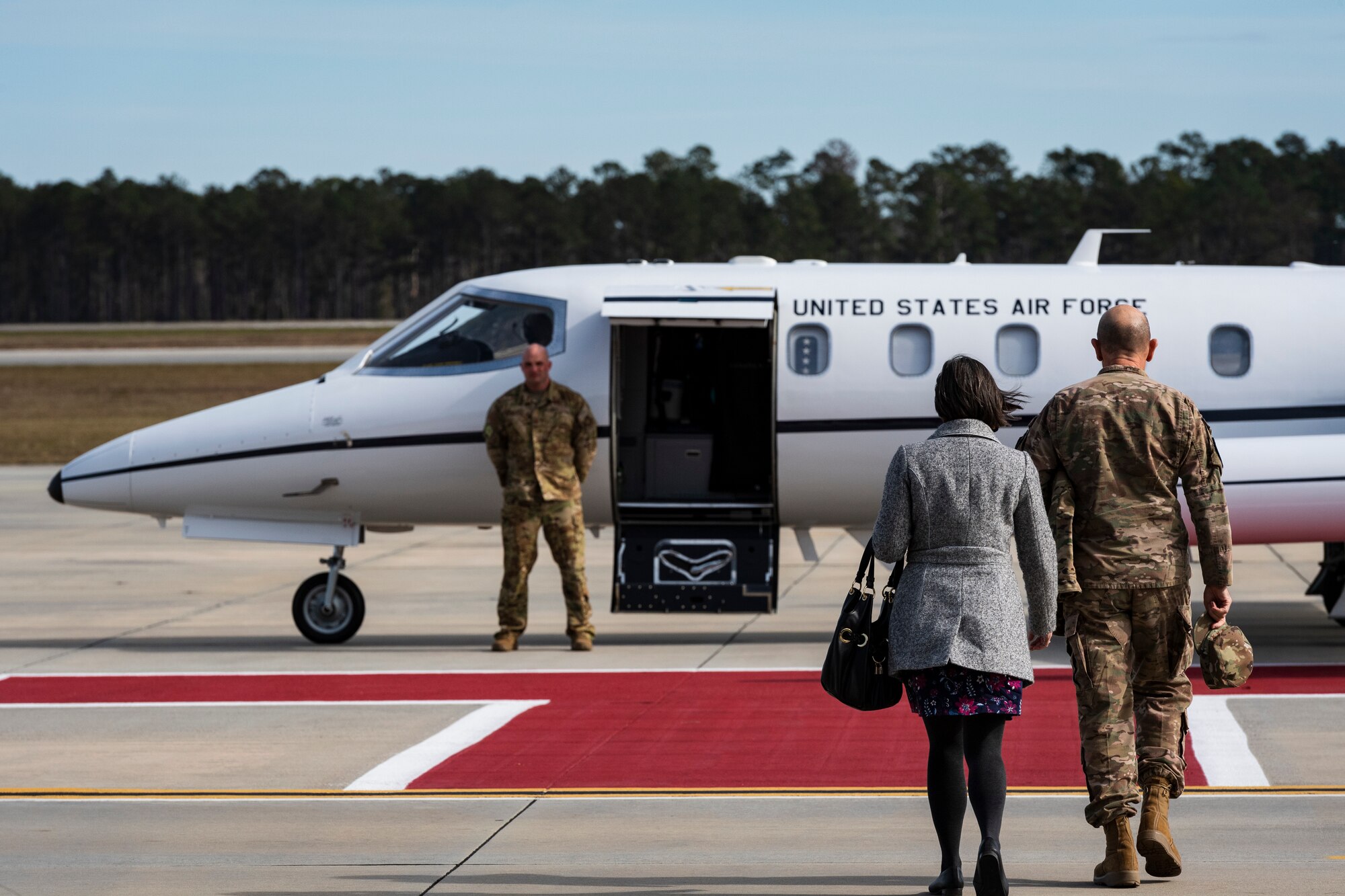 A photo of an Airman and his wife walking to an aircraft