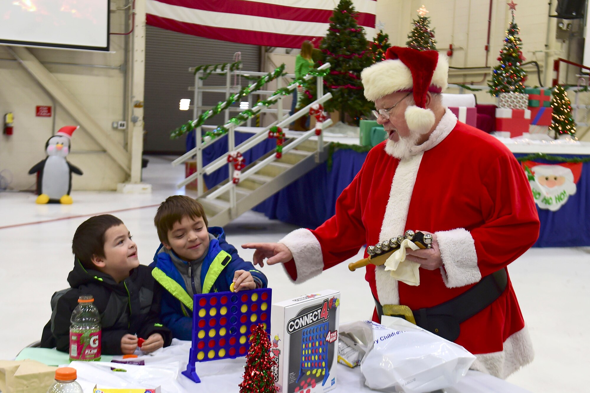 Santa greets Connor and Isidoro Mata while they play a game during the Kids’ Christmas Party at Grissom Air Reserve Base, Indiana, Dec. 7, 2019.  The 434th Force Support Squadron Airman and Family Readiness Center transformed Dock 1 into a Christmas wonderland complete with cookie decorating, toys and hot cocoa.  (U.S. Air Force Photo by Staff Sgt. Chris Massey)