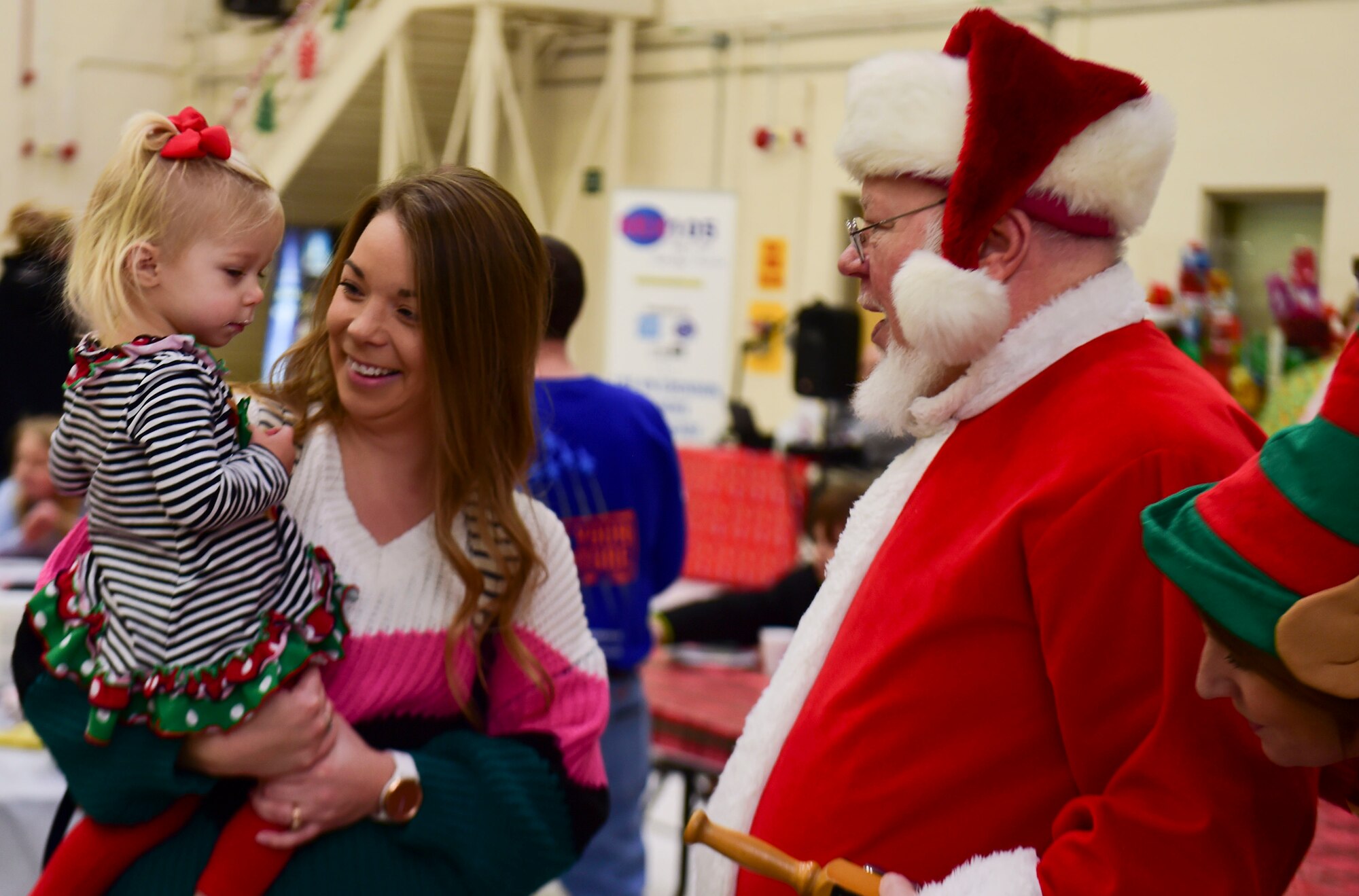 Emilia, held by her mother Jennifer Osborne, meets Santa and his elf during the Kids’ Christmas Party at Grissom Air Reserve Base, Indiana, Dec. 7, 2019.  The 434th Force Support Squadron Airman and Family Readiness Center transformed Dock 1 into a Christmas wonderland complete with cookie decorating, toys and hot cocoa.  (U.S. Air Force Photo by Staff Sgt. Chris Massey)