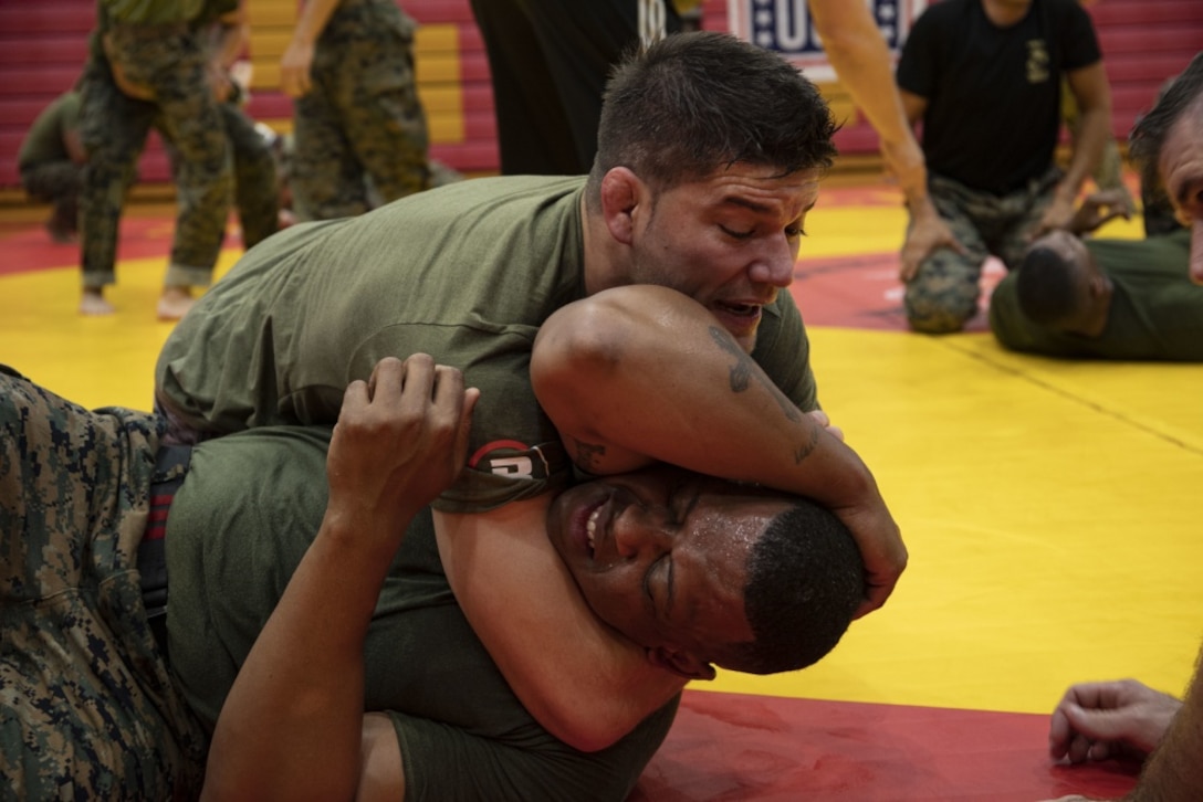Josh Thomson, Mixed Martial Arts (MMA) fighter, performs a choke on a U.S. Marine during an MMA clinic, Semper Fit Center, Marine Corps Base Hawaii (MCBH), Dec. 16, 2019. MMA fighters visited MCBH in support of Salute the Troops, an MMA fighting event dedicated to military personnel and their families. (U.S. Marine Corps photo by Lance Cpl. Samantha Sanchez)