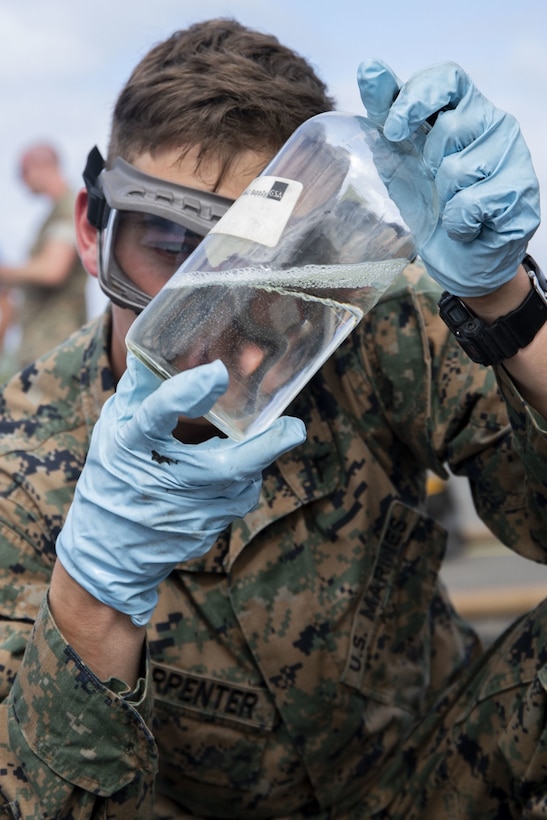 U.S. Marine Corps Lance Cpl. Zachary Carpenter, bulk fuel specialist, Marine Wing Support Squadron (MWSS) 171, shakes a bottle of fuel during an Expeditionary Mobile Fuel Additization Capability (EMFAC) exercise, MCBH, Dec. 18, 2019. The EMFAC was developed to supplement the supply provided by Defense Logistics Agency Energy, the primary agency responsible for providing the Marine Corps with additized fuel. Marines with MWSS-171, MWSS-172, and Marine Wing Support Detachment 24 participated in this training to increase efficiency and teamwork between the units. (U.S. Marine Corps photo by Lance Cpl. Samantha Sanchez)