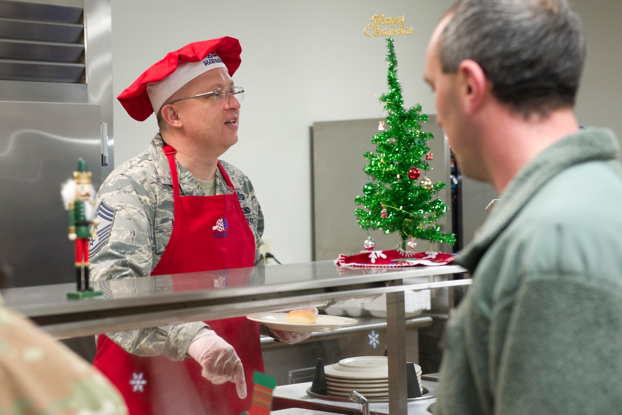 Chief Master Sgt. Wes Marion, 434th Air Refueling Wing command chief, serves lunch to Airmen in the dining facility at Grissom Air Reserve Base, Indiana, Dec. 7, 2019. Wing leadership and GCC members helped served holiday staples prepared by the 434th Force Support Squadron during the December Unit Training Assembly. (U.S. Air Force photo/ Staff Sgt. Courtney Dotson-Essett)