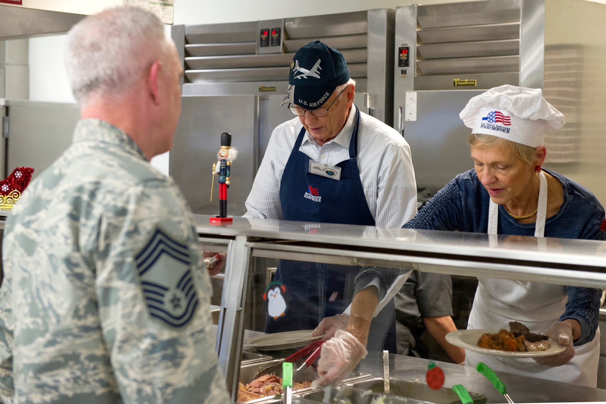 Members of the Grissom Community Council serve a holiday-themed meal in the dining facility at Grissom Air Reserve Base, Indiana, Dec. 7, 2019. The 434th Force Support Squadron prepared turkey, ham, stuffing and other holiday staples during the December Unit Training Assembly in anticipation of serving hundreds of hungry members. (U.S. Air Force photo/ Staff Sgt. Courtney Dotson-Essett)