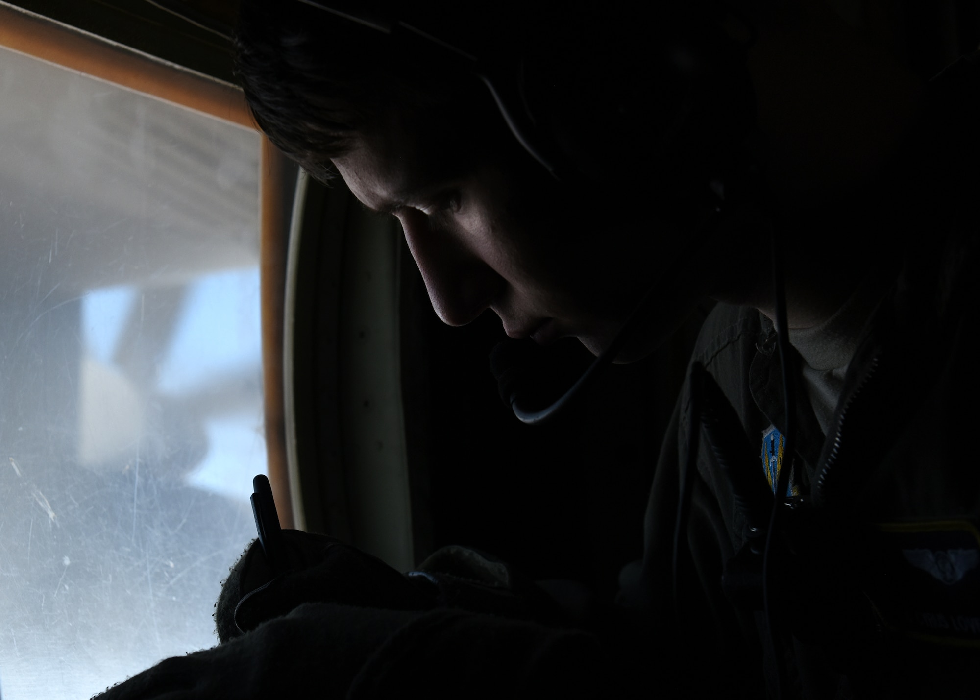 Photo of an Airman writing down job tasks in his journal during an aerial refueling mission