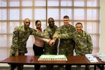 Members of the Eighth Army Chaplains Directorate prepare to cut a cake during a unit function that focused on the 110 years of the religious affairs specialist career field in the U.S. Army at U.S. Army Garrison-Humphreys, South Korea, Dec. 19.