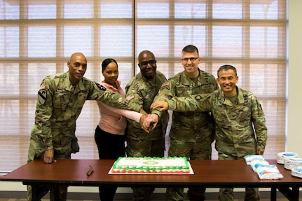 Members of the Eighth Army Chaplains Directorate prepare to cut a cake during a unit function that focused on the 110 years of the religious affairs specialist career field in the U.S. Army at U.S. Army Garrison-Humphreys, South Korea, Dec. 19.