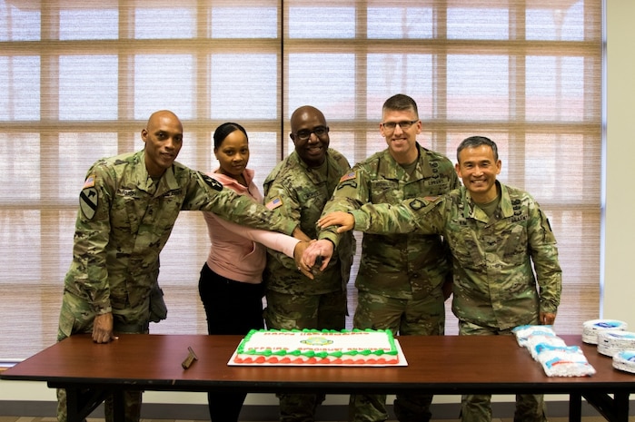Members of the Eighth Army Chaplains Directorate prepare to cut a cake during a unit function that focused on the 110 years of the religious affairs specialist career field in the U.S. Army at U.S. Army Garrison-Humphreys, South Korea, Dec. 19.