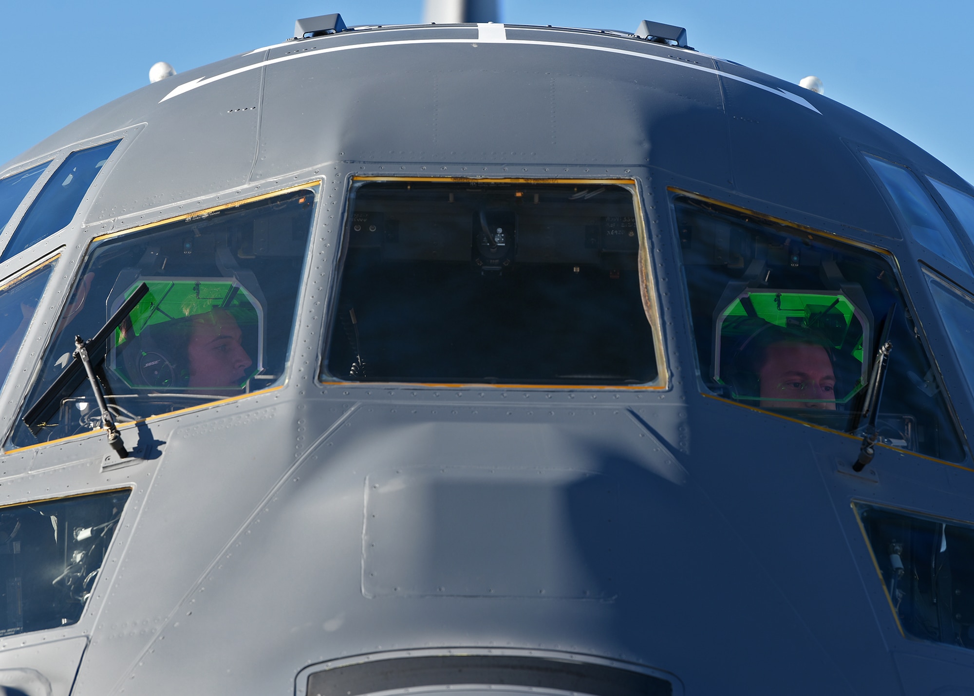 Photo of two U.S. Air Force carrier aircraft pilots performing pre-flight tasks in the cockpit