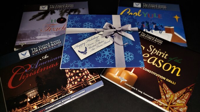 Picture of five compact disc cases for various holiday recordings by The U.S. Air Force Band in Washington, D.C. The cover for each album features holiday graphics and imagery such as Christmas trees and snowflakes.