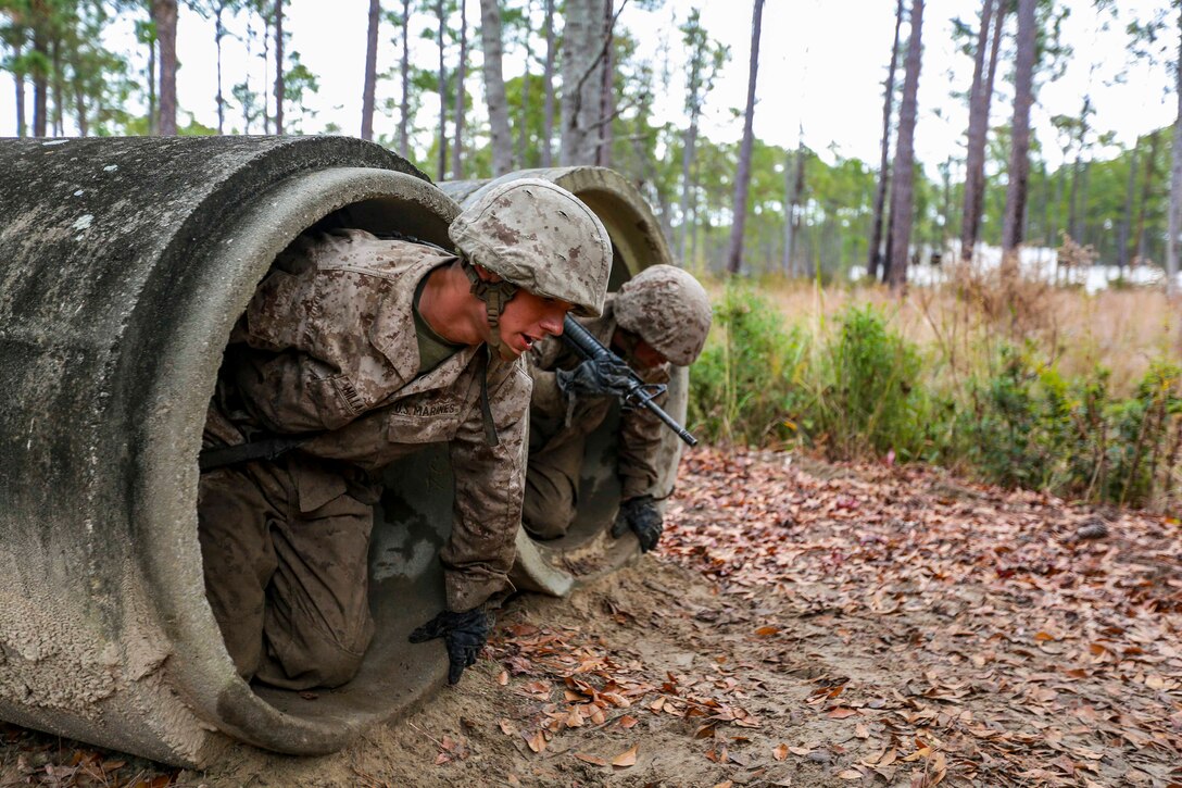 Two Marines climb out of a large tube.