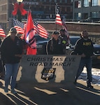 Volunteers Sean Leombruno, right, and Melanie Howard, left, hold the banner for the Christmas Eve Road March in Glens Falls, N.Y. to support deployed troops and veterans Dec. 24, 2019. Hundreds of military families, veterans and community members joined Army and Air National Guard members and event coordinators retired Army National Guard Sgt. 1st Class Arthur Coon, second from right, and his wife, Julie, for the annual event.