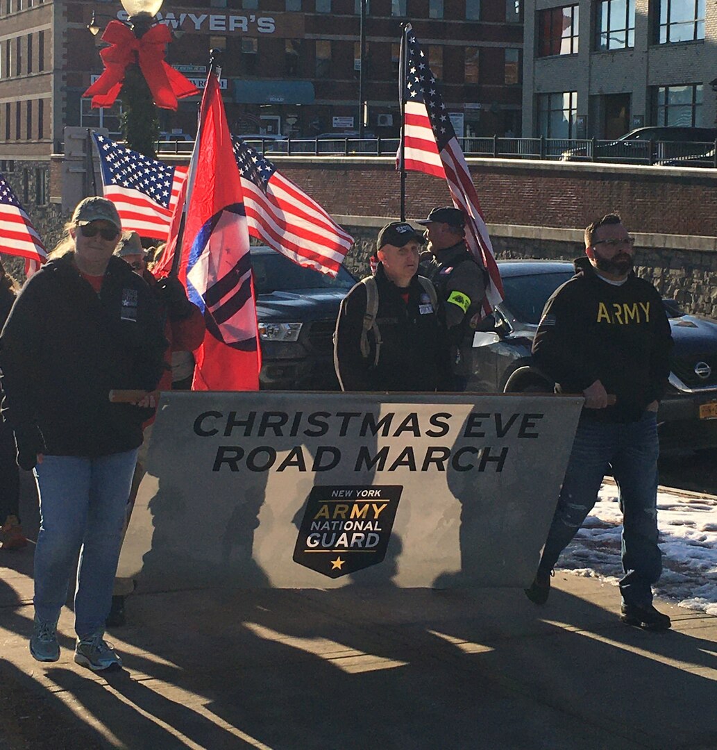 Volunteers Sean Leombruno, right, and Melanie Howard, left, hold the banner for the Christmas Eve Road March in Glens Falls, N.Y. to support deployed troops and veterans Dec. 24, 2019. Hundreds of military families, veterans and community members joined Army and Air National Guard members and event coordinators retired Army National Guard Sgt. 1st Class Arthur Coon, second from right, and his wife, Julie, for the annual event.