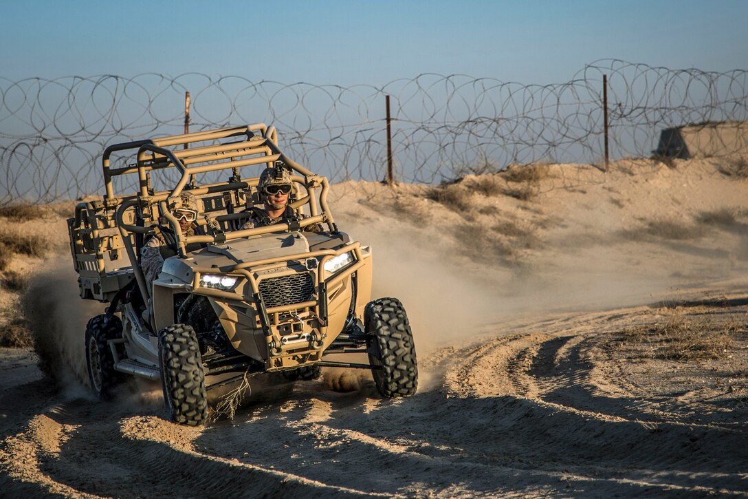 Two Marines drive in a utility vehicle.