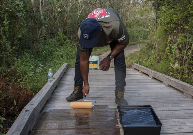 A U.S. Marine applies a waterproofing solution to a wooden bridge during a Single Marine Program volunteer event at Fort Macon State Park, N.C., Sept. 2.