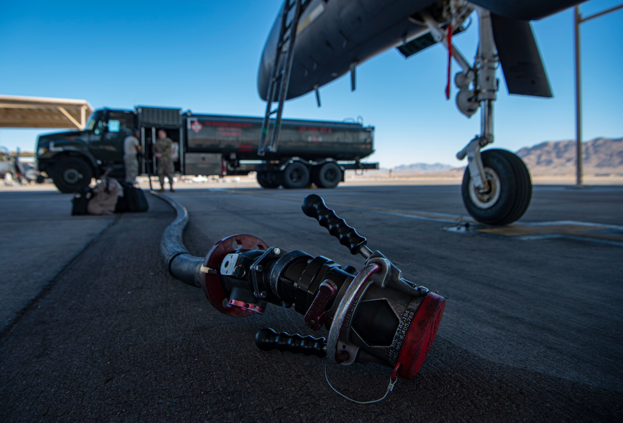 A fuel hose sits underneath a F-15E Strike Eagle fighter jet on the flight line.