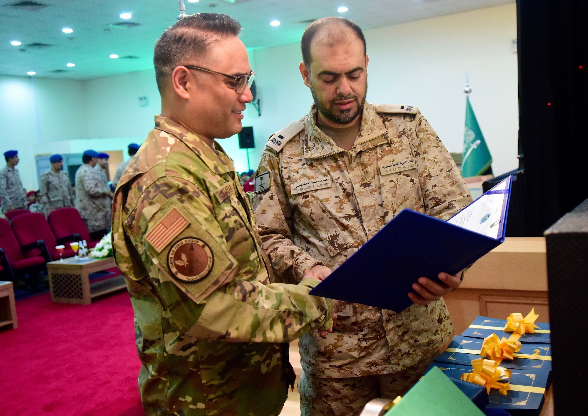 U.S. Air Force Col. Ronald M. Llantada, U.S. Military Training Mission- Kingdom of Saudi Arabia chief, reviews the graduation certificates and awards from the Royal Saudi Air Force’s first SNCO professional military education program graduation ceremony with Chief Master Sgt. of the Royal Saudi Air Force Mohammed Alosaimi on Dec. 11, 2019, at King Solomon Air Base, Kingdom of Saudi Arabia.