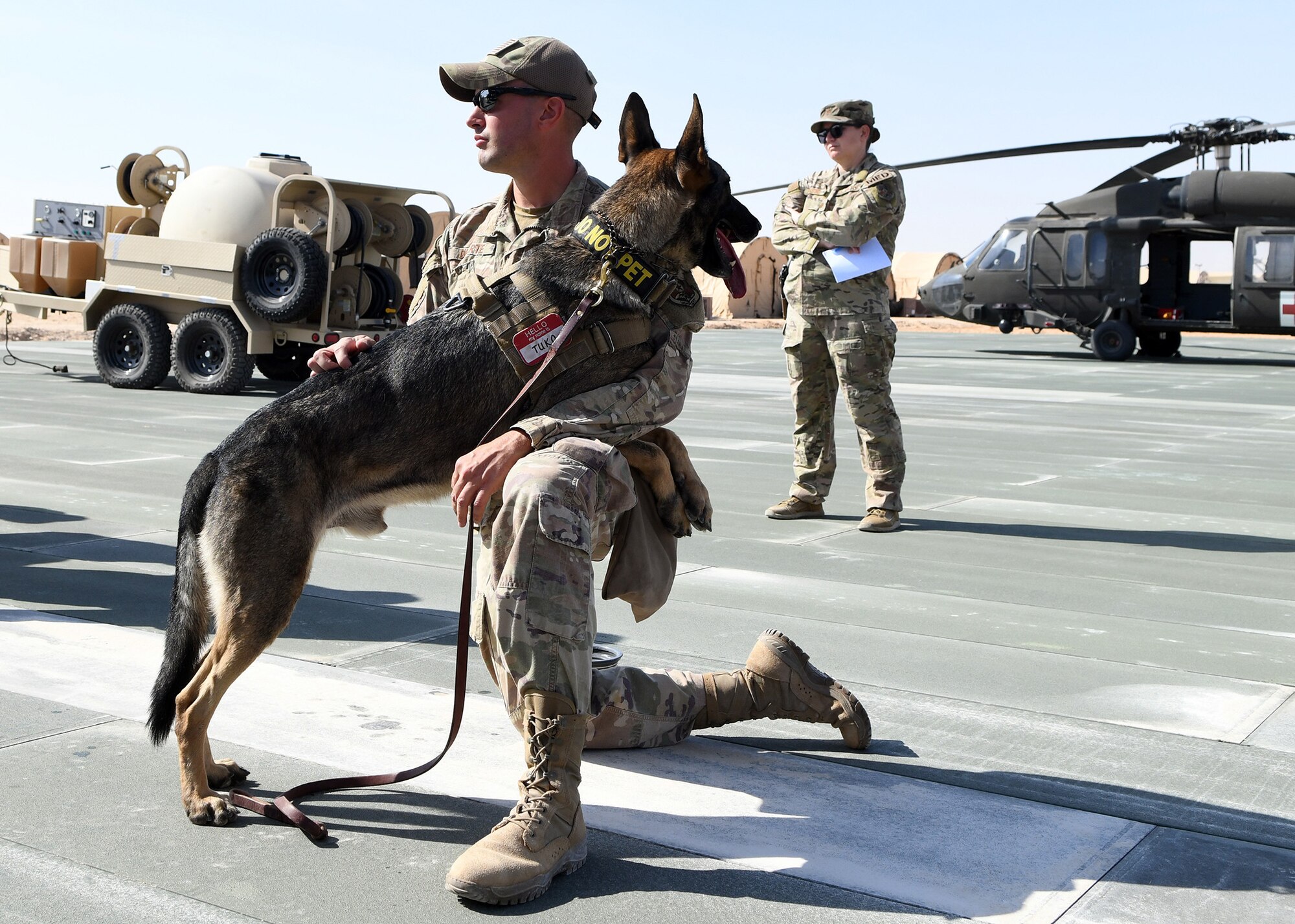 U.S. Air Force Staff Sgt. Daniel Duarte, 378th Expeditionary Security Forces Squadron K-9 handler, and his military working dog, Tuko, watch as U.S. Army personnel brief on medical evacuation techniques at Prince Sultan Air Base, Saudi Arabi, Nov. 27, 2019.
