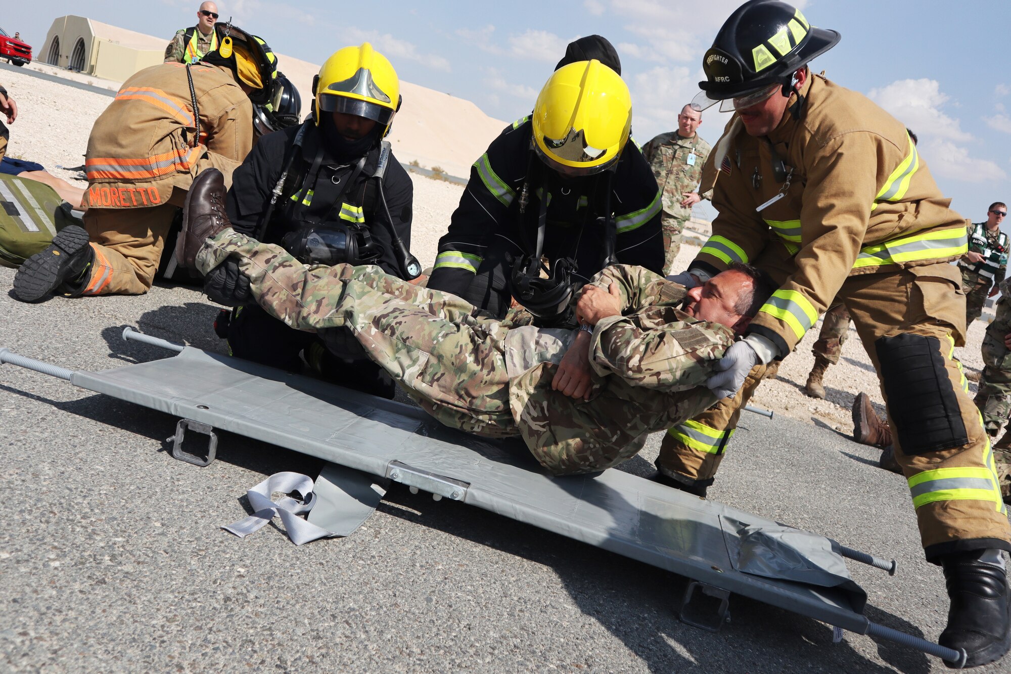 Firefighters from the 379th Expeditionary Civil Engineer Squadron and Qatar Emiri Air Force lift a simulated accident victim onto a litter during a major accident response exercise at Al Udeid Air Base, Qatar on Nov. 12, 2019. The MARE was developed by U.S. Air Force and Royal Air Force planners in order to increase coalition partner interoperability during an emergency situation.(U.S. Air Force photo by Tech. Sgt. Ian Dean)