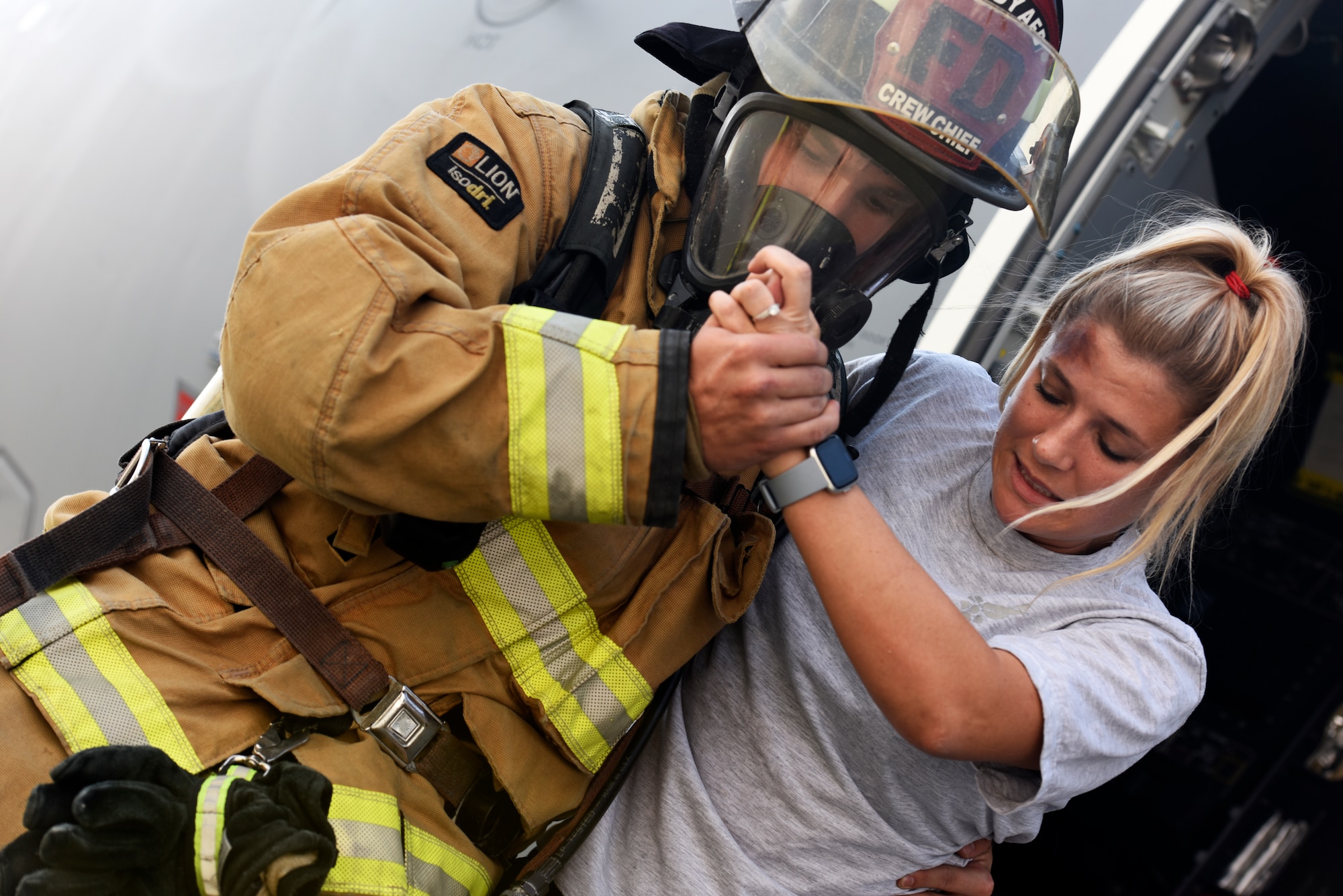 A firefighter from the 379th Expeditionary Civil Engineer Squadron assists a simulated accident victim from a Royal Air Force A400M Atlas aircraft during a major accident response exercise at Al Udeid Air Base, Qatar on Nov. 12, 2019. The MARE was developed by U.S. Air Force and RAF planners in order to increase coalition partner interoperability during an emergency situation.(U.S. Air Force phot by Tech. Sgt. Ian Dean)