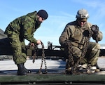 Virginia National Guard personnel and Canadian soldiers offload howitzers and other equipment from trucks Dec. 8, 2019, at Fort Pickett, Virginia. VNG Soldiers assigned to the 1032nd Transportation Company, 1030th Transportation Battalion, 329th Regional Support Group, conducted a line haul to help the Montreal-based 34th Canadian Brigade Group move equipment to Fort Pickett for a training exercise planned in January.