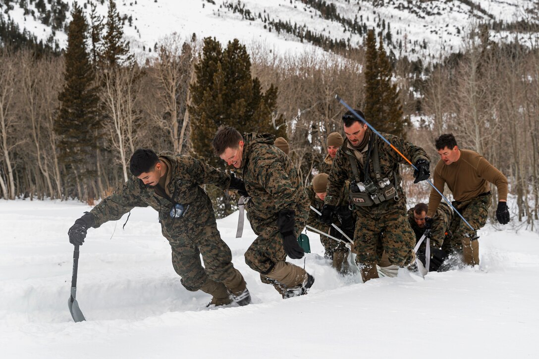 Marines drag a makeshift litter through snow  in the mountains.