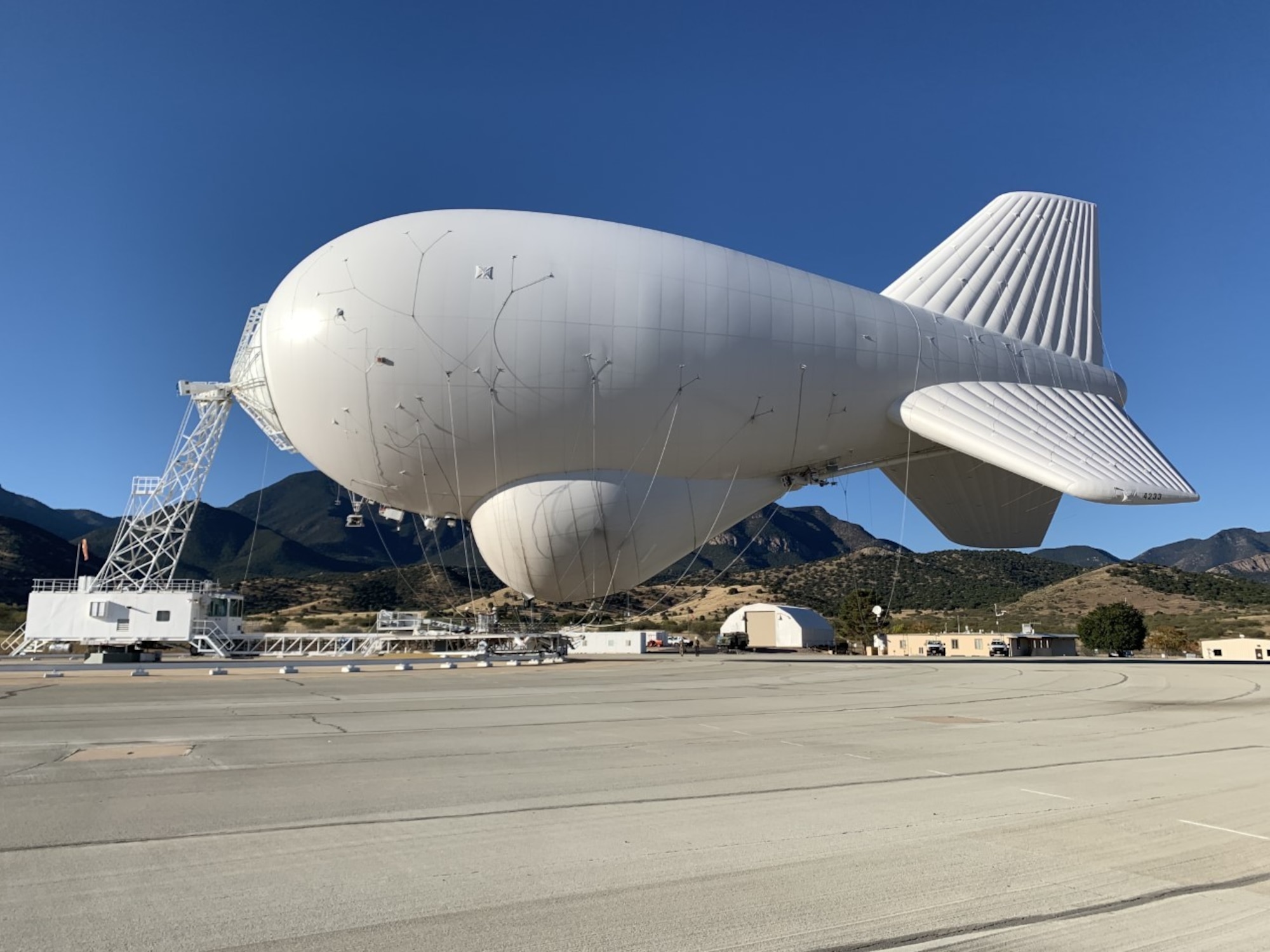 Image is a tethered aerostat radar system (TARS) device being optimized by personnel.