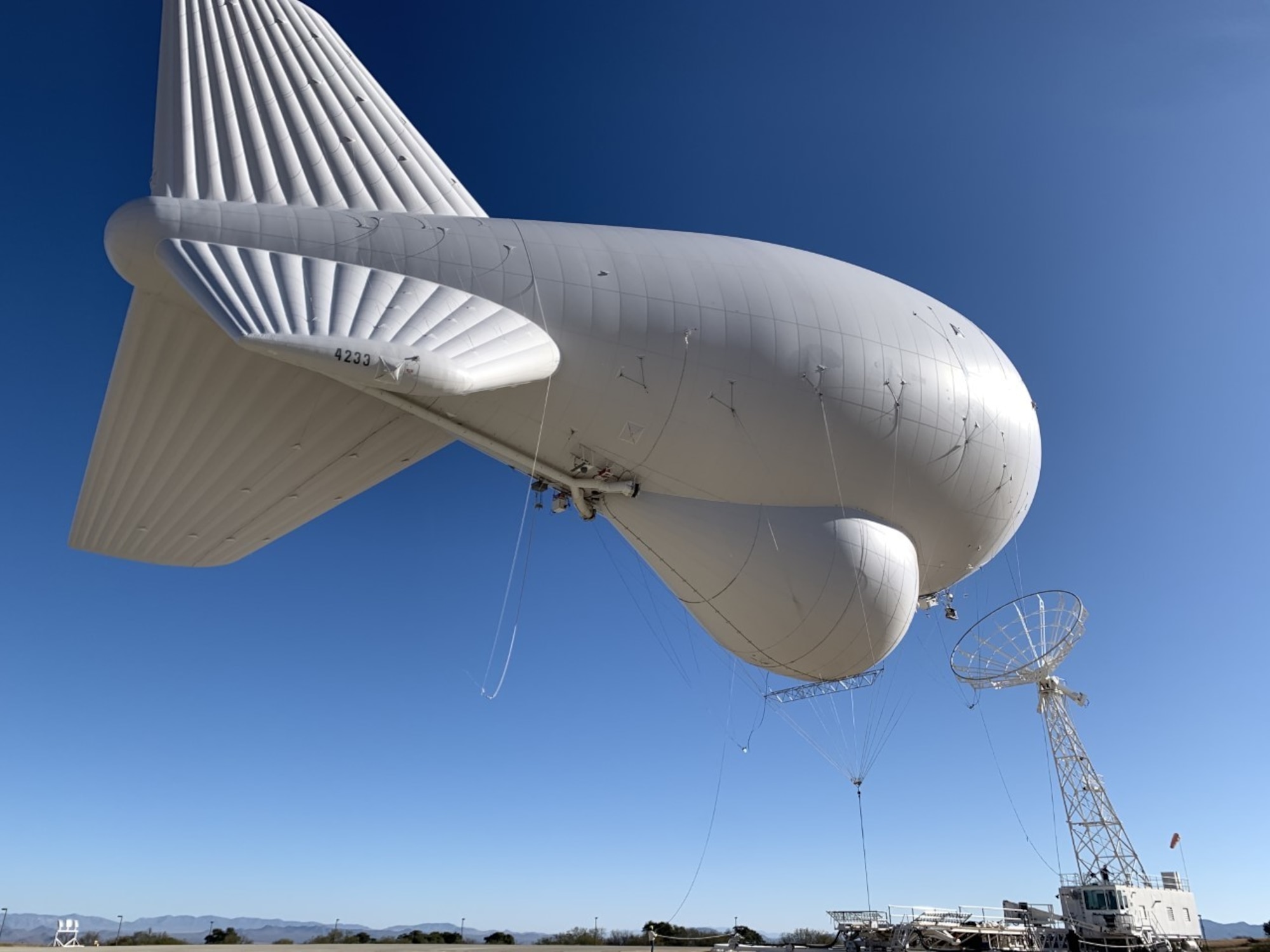 Image is a tethered aerostat radar system (TARS) device being optimized by personnel.