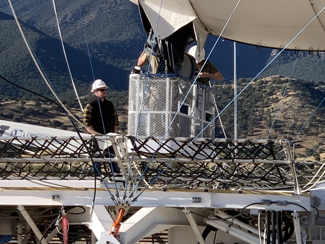 Image is a tethered aerostat radar system (TARS) device being optimized by personnel.
