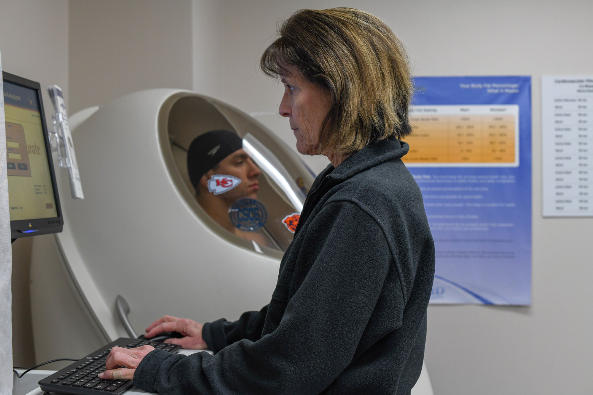 Maribeth Havaran, 22nd Medical Group health promotion dietitian, inputs data into a computer during a Bod Pod scan Dec. 31, 2019, at McConnell Air Force Base, Kan. The first week of January marks Diet Resolution Week; a perfect opportunity for Airmen to take charge of their health and fitness goals. The Bod Pod is a body composition measuring device that can accurately determine an individual’s body fat percentage and lean muscle mass.  Testing is available to Airmen five days a week, in the Health Promotions office by appointment only. (U.S. Air Force photo by Airman 1st Class Nilsa E. Garcia)