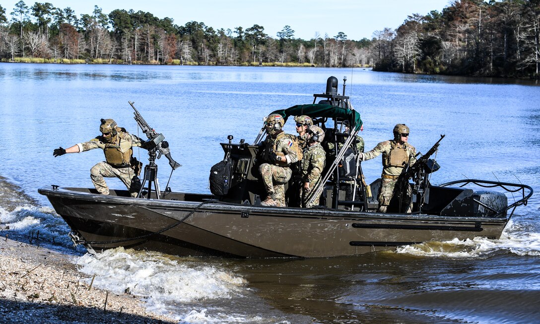 Sailors drive a small boat toward a beach.