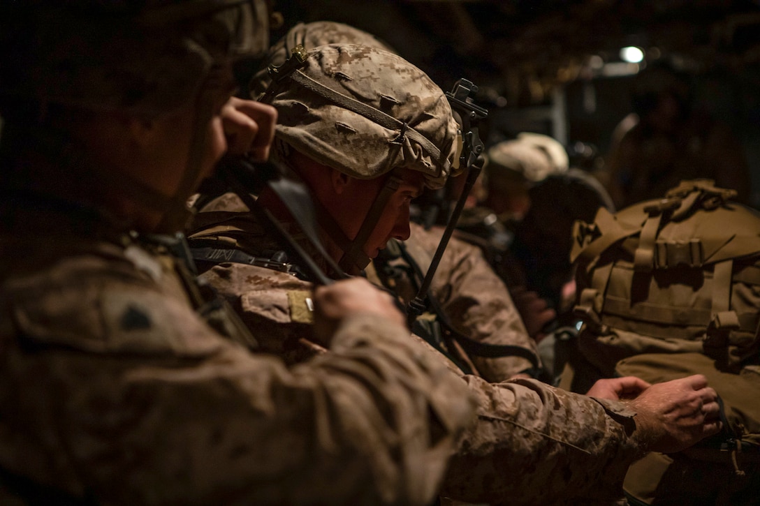 Marines make adjustments to gear while gathered aboard an aircraft