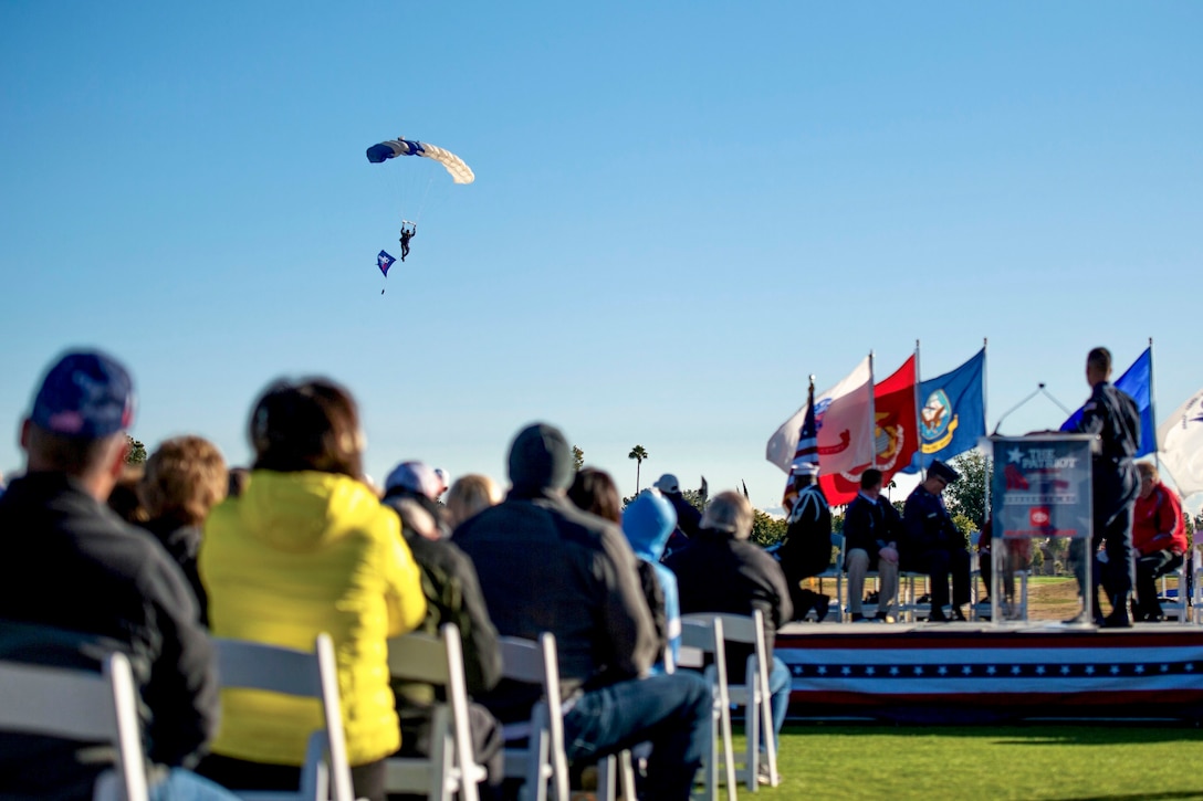 A crowd watches as an Air Force parachutist descends from the sky.