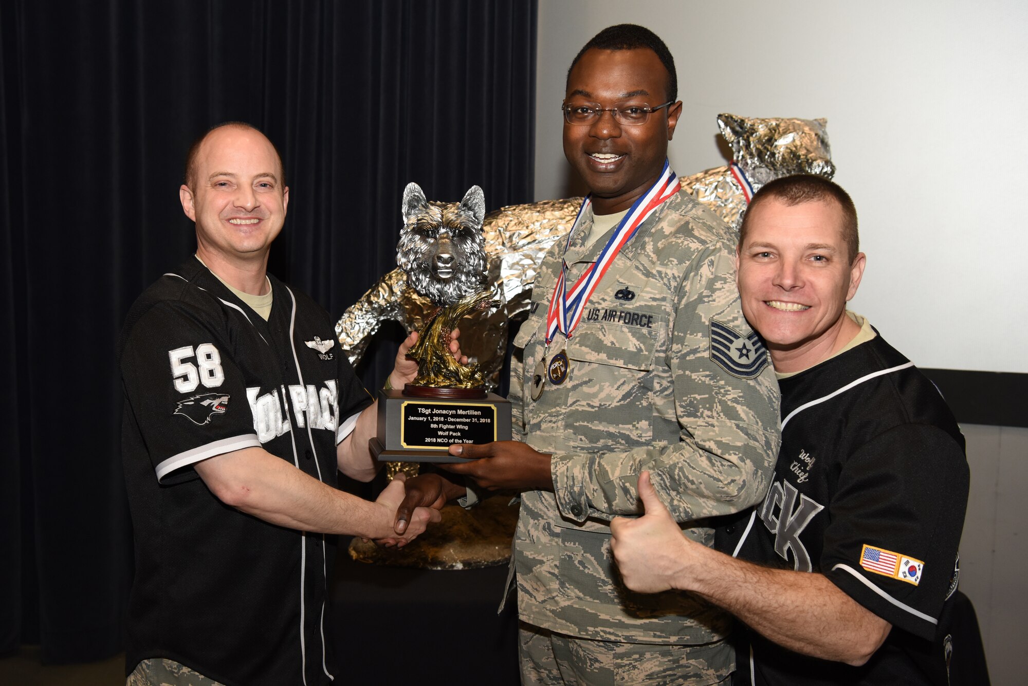U.S. Air Force Col. John Bosone, 8th Fighter Wing commander, and Chief Master Sgt. Michael Moore Jr., 8th FW command chief, present the Noncommissioned Officer of the Year to Tech. Sgt. Jonacyn Mertilien, 8th Maintenance Squadron, at Kunsan Air Base, Republic of Korea, Feb. 1, 2019. The Kunsan annual award winners will go on to compete at the 7th Air Force level. (U.S. Air Force photo by Staff Sgt. Joshua Edwards)
