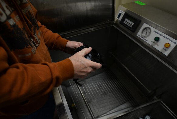 Tom Weise, 375th Logistic Readiness Squadron individual protective equipment specialist, dries off an M50 gas mask after it has gone through a gas mask washer, Jan. 28, 2019, at Scott Air Force Base, Illinois. Many bases still use the hand washing method but Scott AFB is able to wash multiple masks at once to save time.
