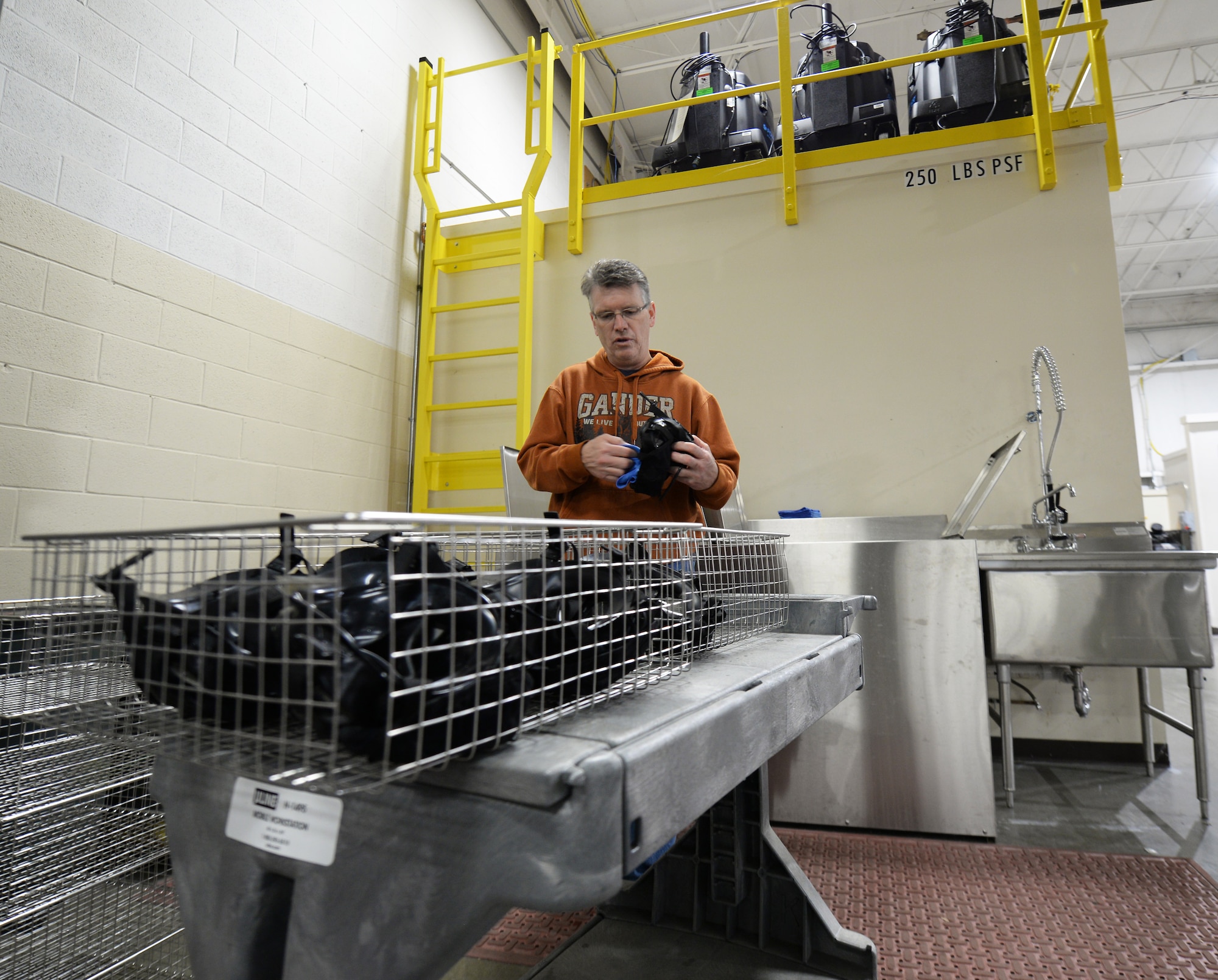 Tom Weise, 375th Logistic Readiness Squadron individual protective equipment specialist, places M50 gas masks in metal baskets before putting them in the gas mask dryer, Jan. 28, 2019, at Scott Air Force Base, Illinois. The dryer allows the gas masks to be put back out for distribution quicker than if they were air dried. This enables more Airmen to be able to get equipment all at once.