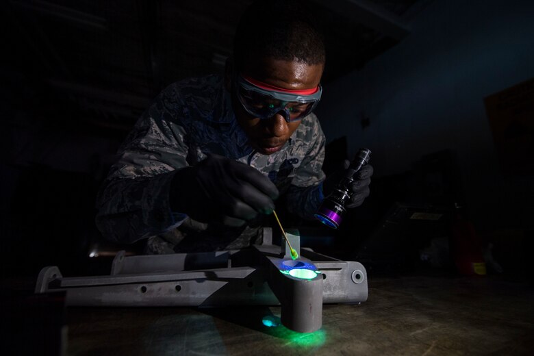 An Airman inspects a piece of equipment with a black light