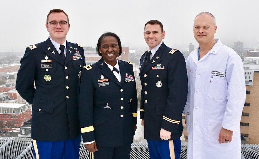 Three Army soldiers stand to the left of a civilian doctor on a rooftop overlooking Camden, N.J.