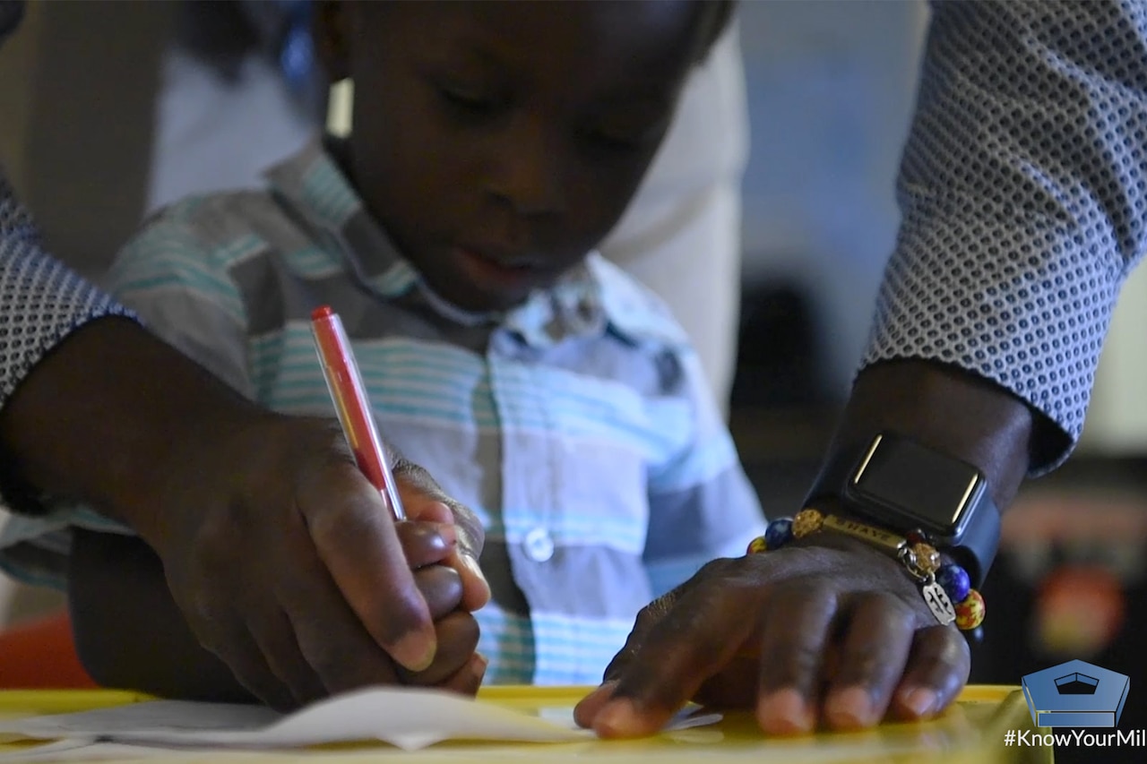 Adult hands helping a child write.