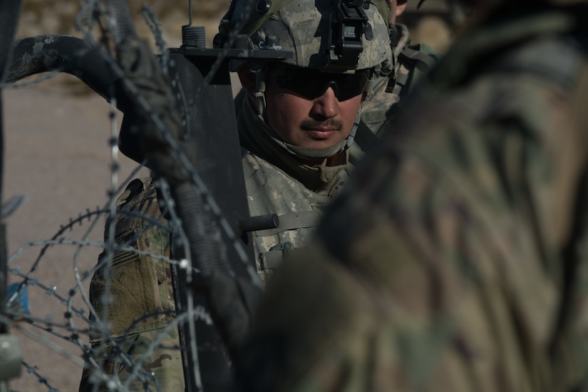 A soldier from the 391st MAC separates pickets, barbed wire and concertina wire before 3rd platoon builds a frag fence.