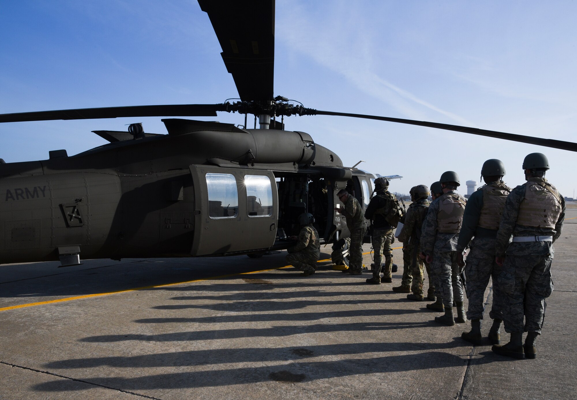 Long shadows are cast upon the flight line as members of the 137th Special Operations Wing, Oklahoma Air National Guard, line up to board an Oklahoma Army National Guard UH-60M Black Hawk at Tinker Air Force Base during SENTRY REX 19-01 exercise on Jan. 15th.