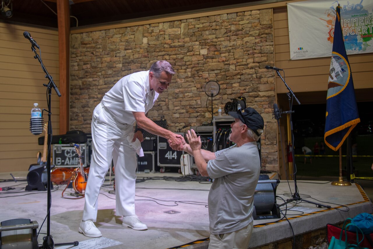 A Navy musician shakes hands with audience member.