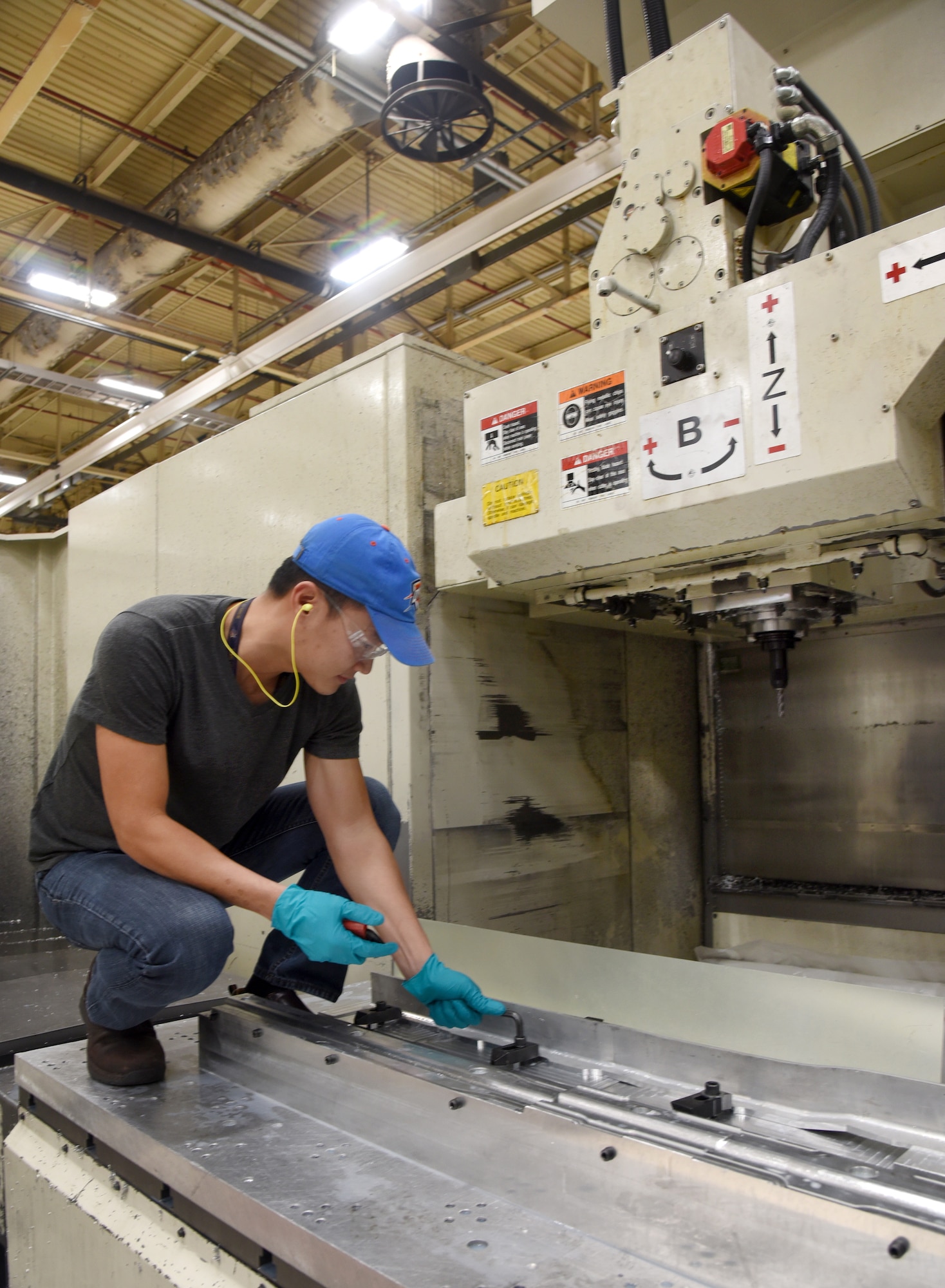 Truyen Ngo, with the 76th Commodities Maintenance Group’s Numerical Control Machine Shop, fastens a keel beam into the SNK-80V CNC Milling Machine, to have specific joggles cut into it so the part will fit perfectly into its designated place on the KC-135 aircraft. (U.S. Air Force photo/Kelly White)